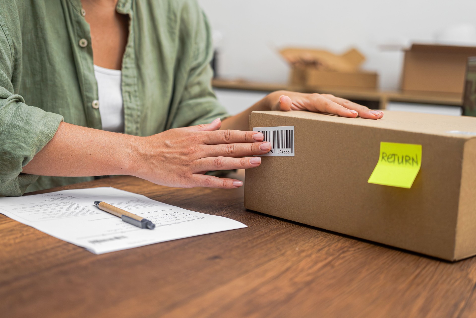 Hands of female consumer stick barcode on cardboard box with yellow sticker with word Return